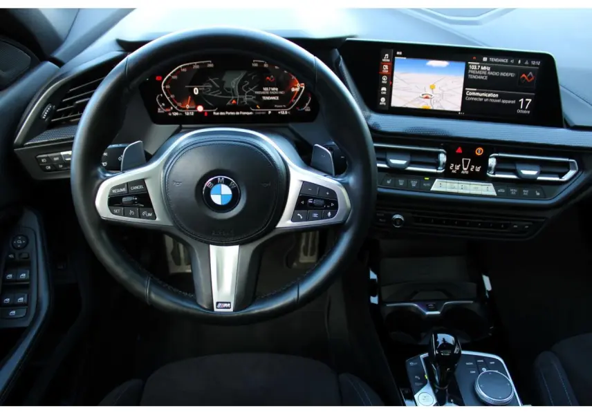 Vue intérieure centrée sur le volant M cuir et le tableau de bord numérique de la BMW Série 1 118d Edition M Sport Pro.