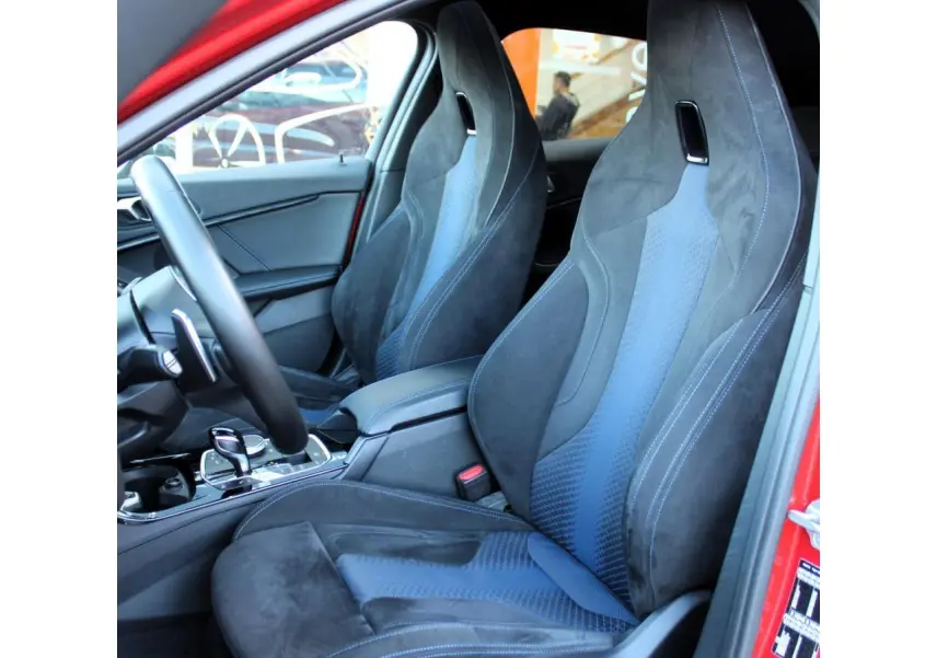 Vue intérieure côté gauche montrant les sièges sport M en tissu Alcantara noir et bleu d'une BMW Série 1 Melbourne Rot.