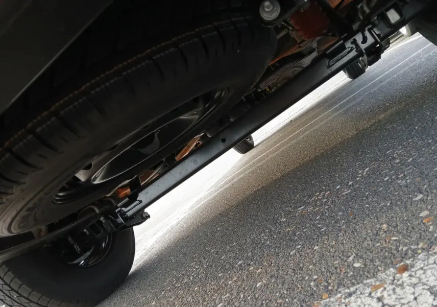 Vue en contre-plongée sous le Renault Master orange, mettant en valeur la roue de secours et le châssis arrière.