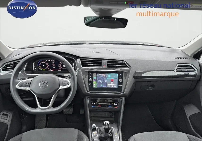 Vue intérieure avant du Volkswagen Tiguan gris lunaire 2022, tableau de bord moderne avec écran tactile et volant multifonction.