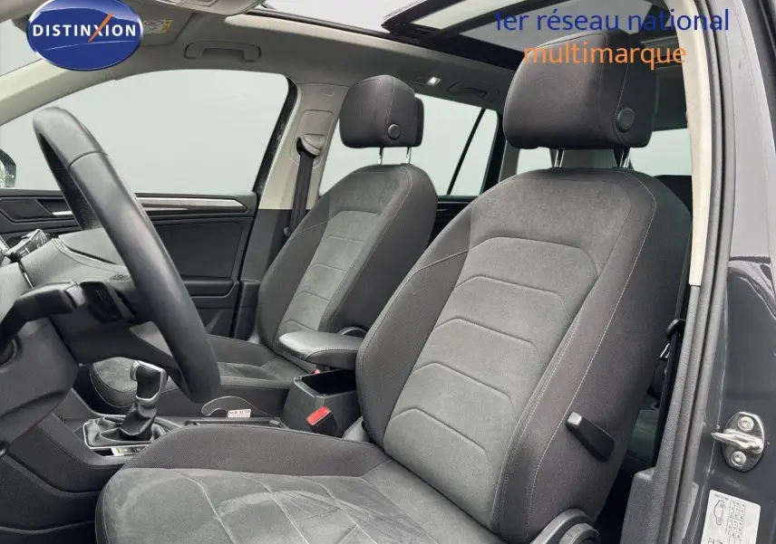Intérieur avant du Volkswagen Tiguan gris lunaire 2022, sièges tissu gris et volant visible côté gauche.