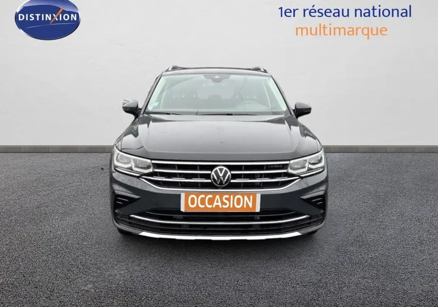 Vue frontale d'un Volkswagen Tiguan gris lunaire 2022 hybride rechargeable avec calandre chromée et logo VW visible.
