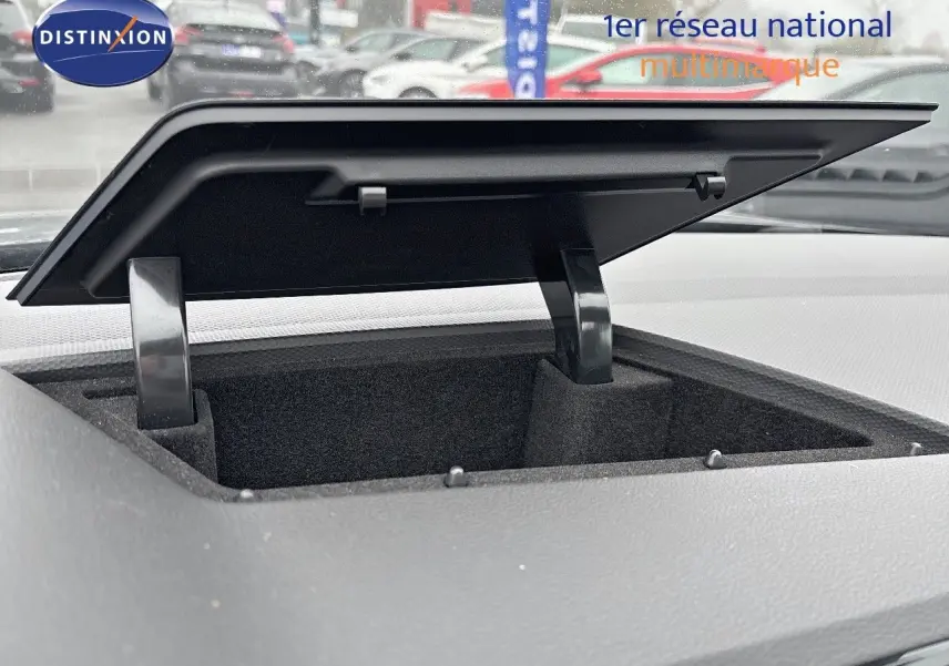 Coffre de rangement ouvert sur le tableau de bord du Volkswagen Tiguan 1.4 e-Hybrid gris lunaire, vue intérieure rapprochée.