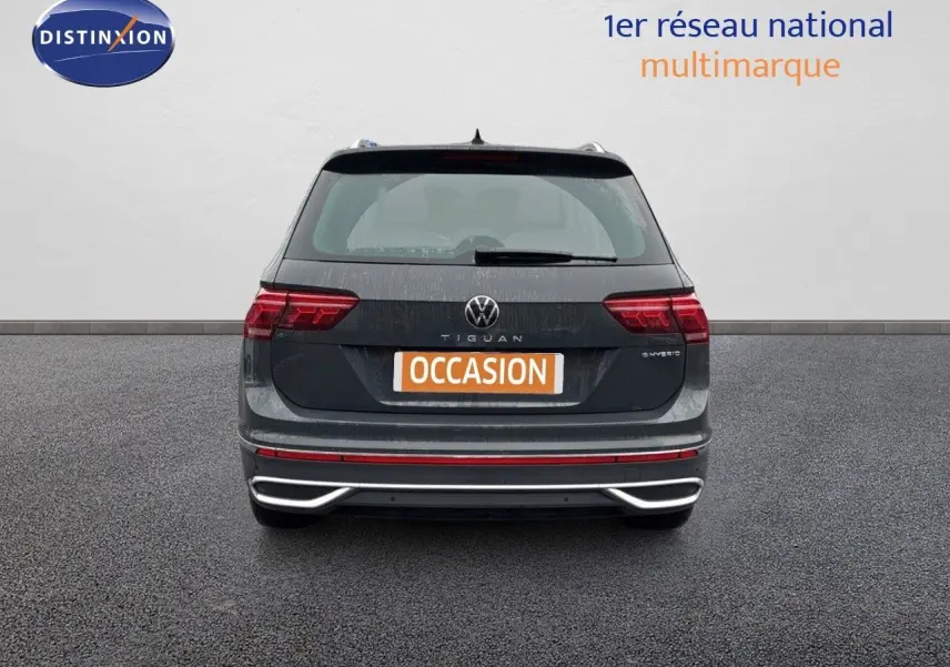Vue arrière d'un Volkswagen Tiguan gris lunaire hybride rechargeable avec feux LED et logo distinctif visible.