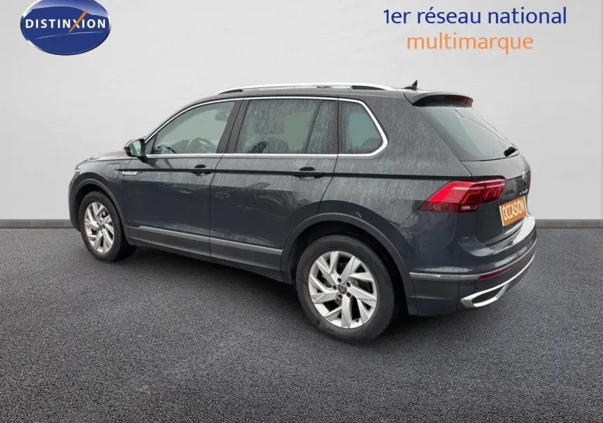 Vue 3/4 arrière côté gauche d'un Volkswagen Tiguan gris lunaire hybride rechargeable de 2022 avec jantes alliage.