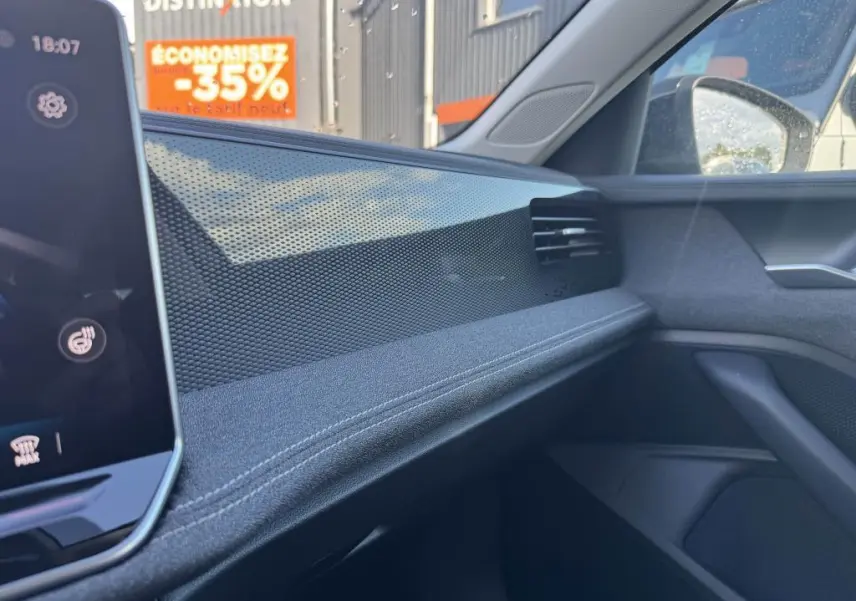 Détail de la planche de bord côté passager de la Volkswagen Passat SW noire 2024 avec finition tissu et inserts décoratifs brillants.