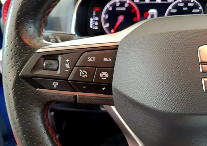 Gros plan sur la partie gauche du volant en cuir noir perforé du SEAT Arona 2022, avec commandes multifonctions visibles.