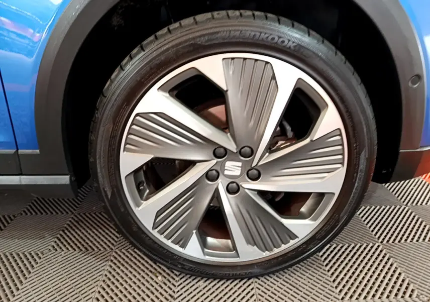 Gros plan sur la jante alliage argentée au design moderne du SEAT Arona bleu, côté roue avant droite.