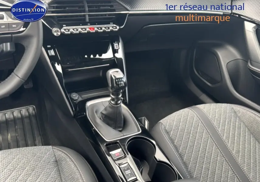 Vue intérieure centrée sur la console centrale et levier de vitesse manuelle, sièges gris tissu embossé dans Peugeot 2008 2025.