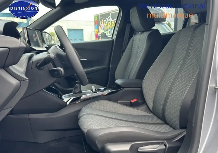 Vue intérieure côté conducteur du Peugeot 2008 gris artense, mettant en valeur les sièges en tissu embossé et la console centrale.