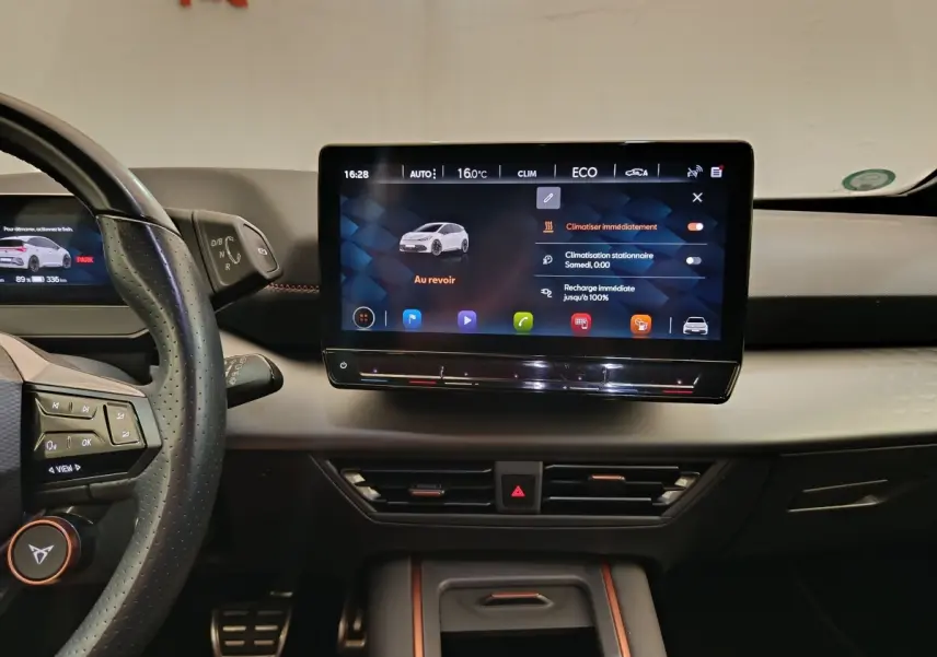 Vue intérieure du tableau de bord du CUPRA Born 230ch, écran tactile central 12 pouces avec interface climatisation et recharge.