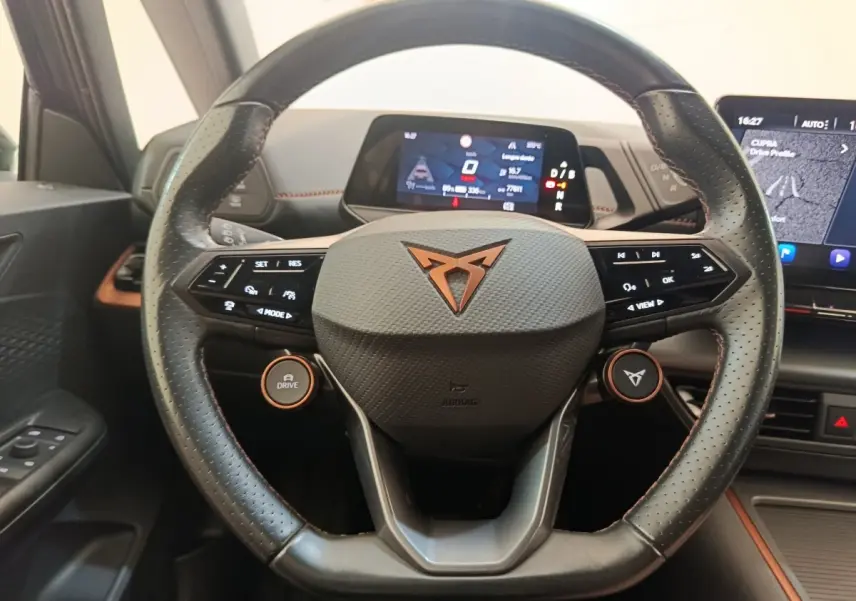 Vue rapprochée du volant cuir noir avec logo CUPRA orange du tableau de bord du CUPRA Born gris foncé 2023 électrique.