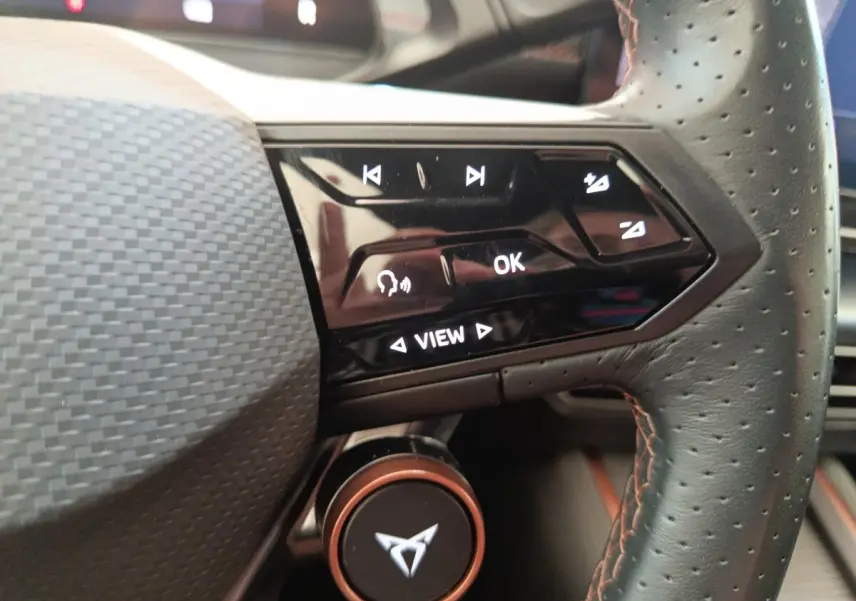 Gros plan sur la partie droite du volant cuir perforé du CUPRA BORN gris foncé, avec commandes tactiles et logo CUPRA central.