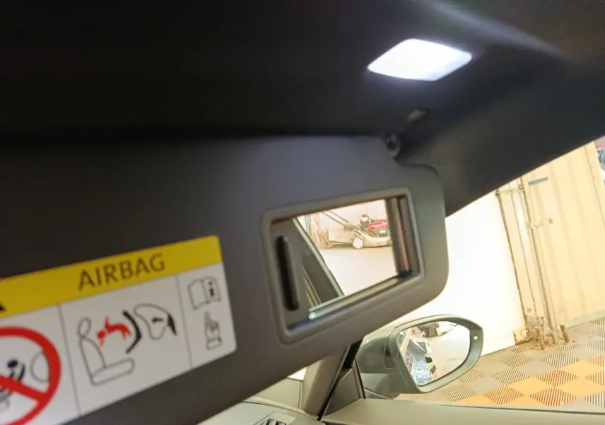 Détail de miroir de courtoisie sur pare-soleil intérieur d’une CUPRA BORN gris foncé, avec rétroviseur latéral visible.
