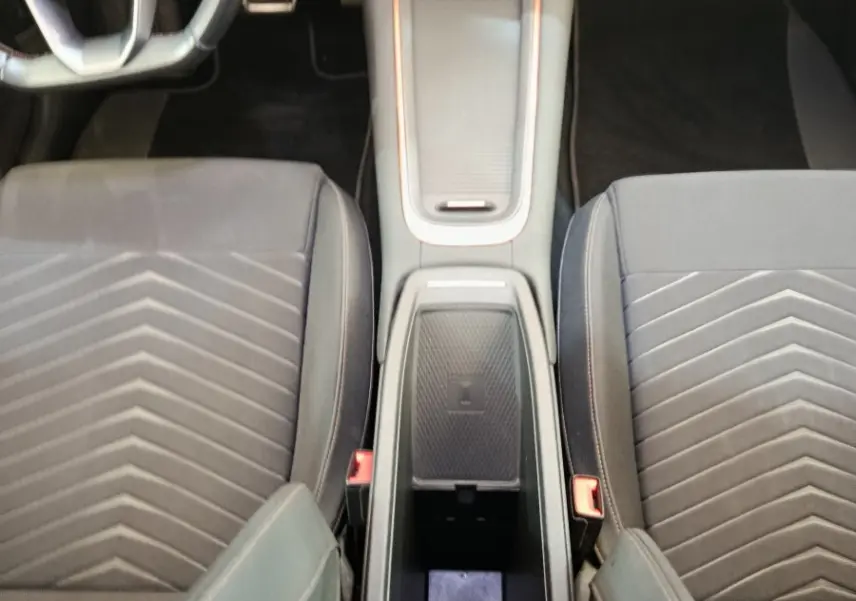 Vue plongeante sur l’intérieur avant du CUPRA BORN gris foncé, montrant la console centrale avec recharge par induction et sièges tissu.