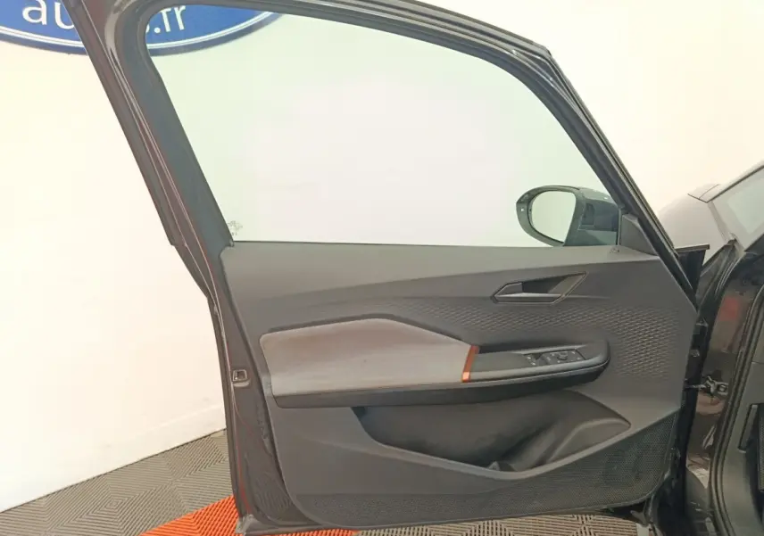 Vue intérieure de la porte avant gauche gris foncé de la CUPRA BORN 230ch avec garniture tissu et commandes électriques.