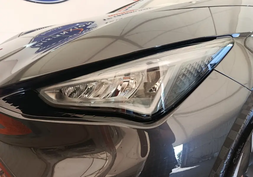 Gros plan sur le phare avant droit du CUPRA BORN gris foncé 2023, soulignant ses lignes anguleuses et détails LED.