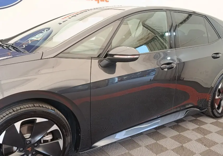 Profil côté gauche de la CUPRA BORN gris foncé 230ch, avec jantes noires et rétroviseurs rabattables électriquement.