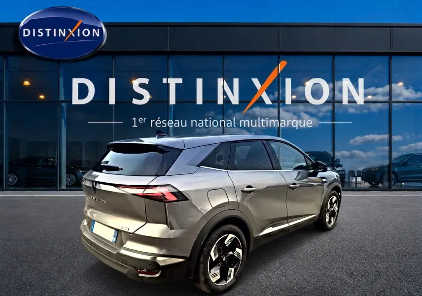Vue 3/4 arrière droite du Renault Symbioz gris cassiope avec jantes alu et feux arrière LED devant un showroom Distinxion.
