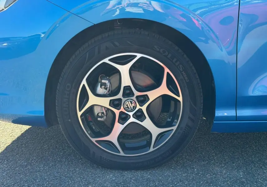 Gros plan sur la roue avant gauche de la MG3 1.5 Hybrid+ 195ch Comfort en Como Blue métallisé avec jante alu distinctive.