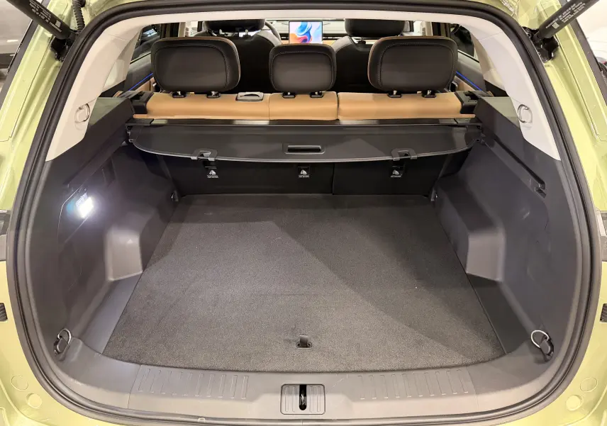 Coffre ouvert vu de l'arrière du JAECOO J7 gris olive, avec banquette arrière cuir brun et cache-bagages déployé.