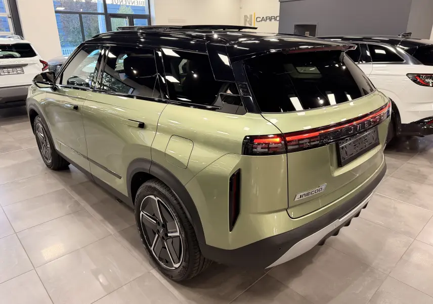 Vue 3/4 arrière droite du SUV hybride rechargeable JAECOO J7 gris olive avec toit noir brillant et feux arrière LED continus.