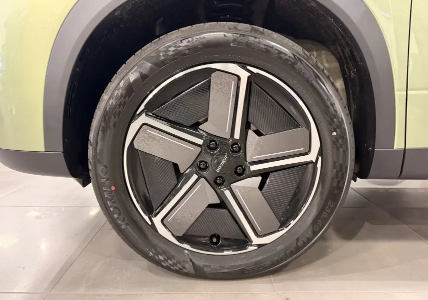 Gros plan sur la roue avant droite du JAECOO J7 gris olive, mettant en valeur la jante noire et argentée au design moderne.