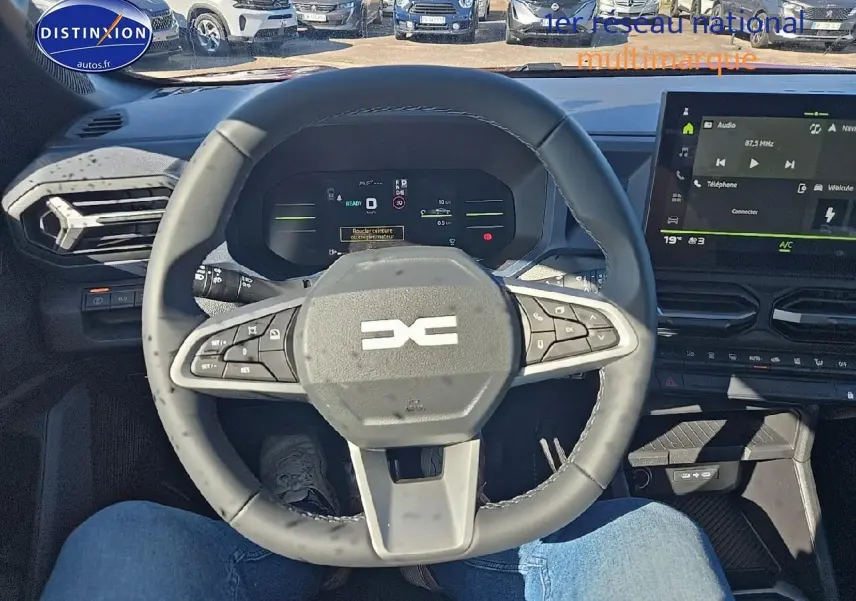 Vue intérieure centrée sur le volant multifonction du Dacia Duster 2025, avec tableau de bord numérique et écran tactile.
