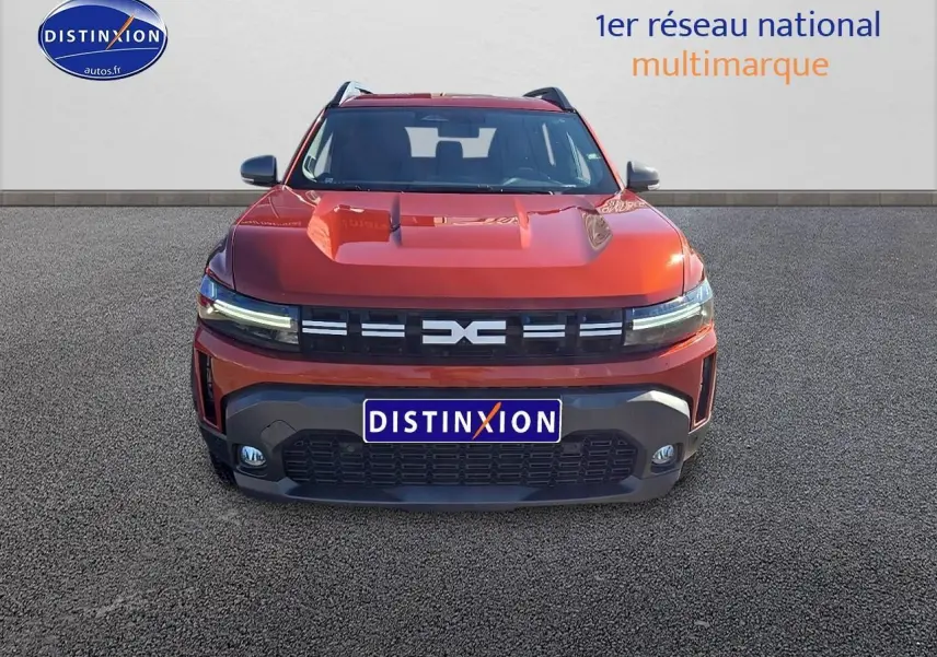 Vue frontale du Dacia Duster 2025 brun terracotta avec calandre noire et phares LED fins allumés.