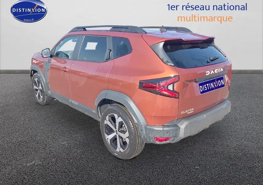 Vue 3/4 arrière droit du Dacia Duster brun terracotta avec barres de toit et jantes alu distinctives.
