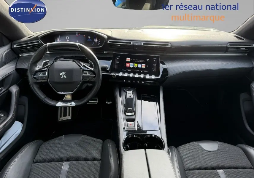 Vue intérieure avant de la Peugeot 508 gris platinium 2023, mettant en valeur le volant compact et l'écran tactile central.