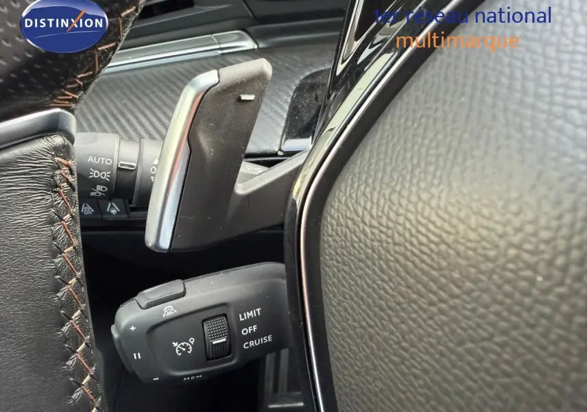 Gros plan sur la commande de régulateur de vitesse au volant cuir noir de la Peugeot 508 gris platinium 2023.