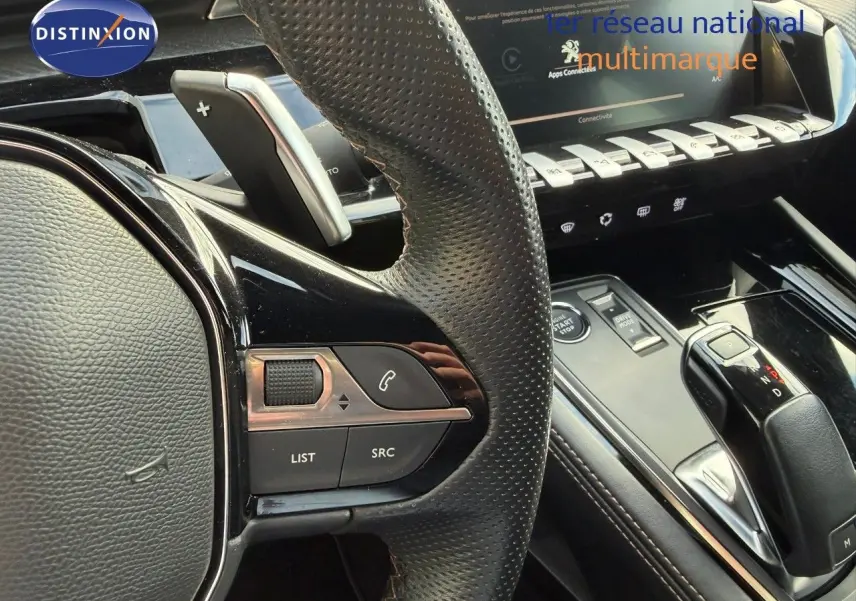 Gros plan sur le volant en cuir perforé et la console centrale noire brillante de la Peugeot 508 gris platinium, version 2023.