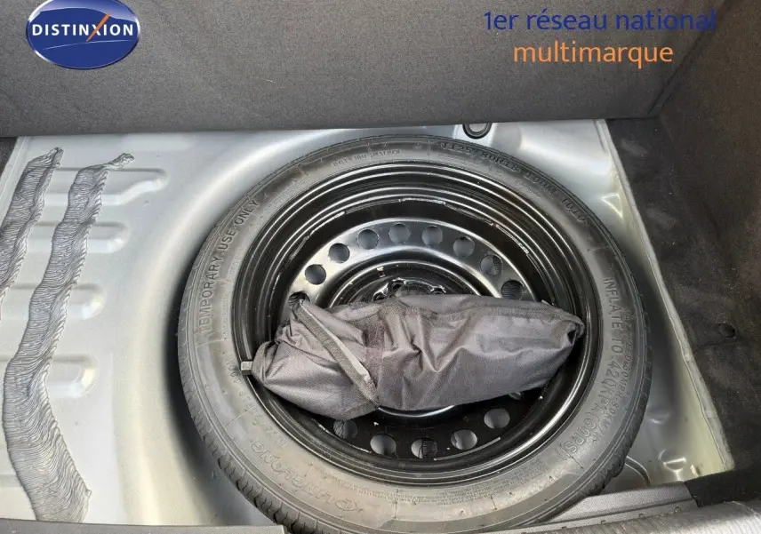 Roue de secours noire dans le coffre d'une Peugeot 508 gris platinium, vue de dessus centrée sur la roue.