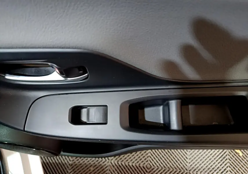 Détail de la commande de lève-vitre côté conducteur sur la porte intérieure noire d'une Toyota Yaris blanche 2020.