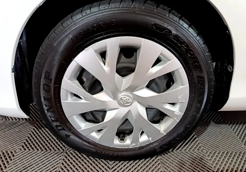 Gros plan sur la roue avant droite blanche d'une Toyota Yaris 1.5 Hybride 2020 avec enjoliveur argenté et logo Toyota central.