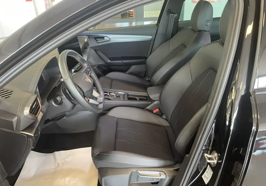 Vue intérieure côté conducteur de la CUPRA Formentor noire 2025, sièges sport en tissu et similicuir avec surpiqûres contrastées.