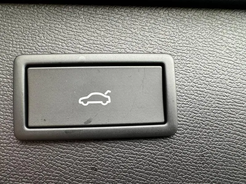 Gros plan sur le bouton d'ouverture électrique du coffre, entouré de plastique noir texturé à l'intérieur du CUPRA Formentor gris Graphène.