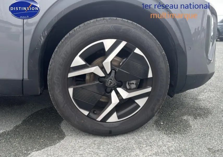 Gros plan sur la roue avant droite d'un Peugeot 2008 gris sélénite avec jante alu au design moderne.