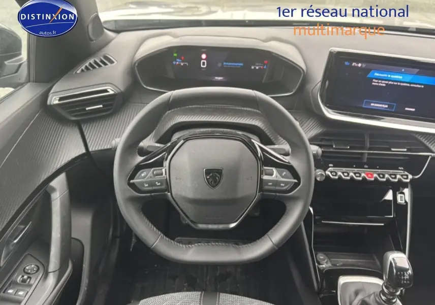 Vue intérieure centrée sur le volant Peugeot 2008 1.2 100 allure, tableau de bord et écran tactile visibles.