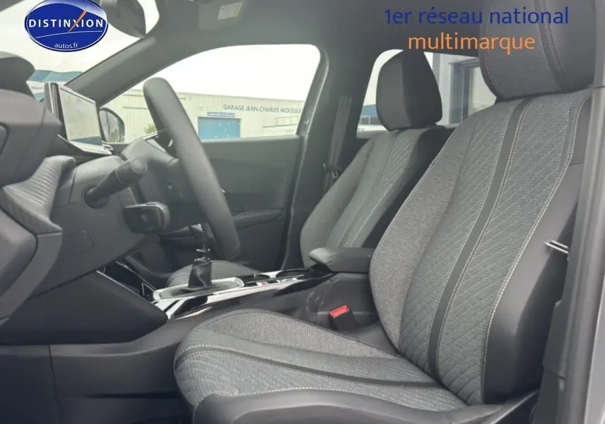 Vue intérieure côté conducteur du Peugeot 2008 1.2 100 allure 2025 avec sièges tissu gris casual lomsa embossé et volant multifonction.