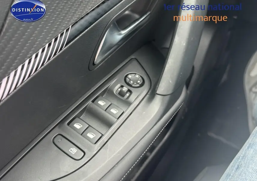 Vue rapprochée des commandes de vitres électriques et rétroviseurs sur la porte côté conducteur d’un Peugeot 2008 gris.
