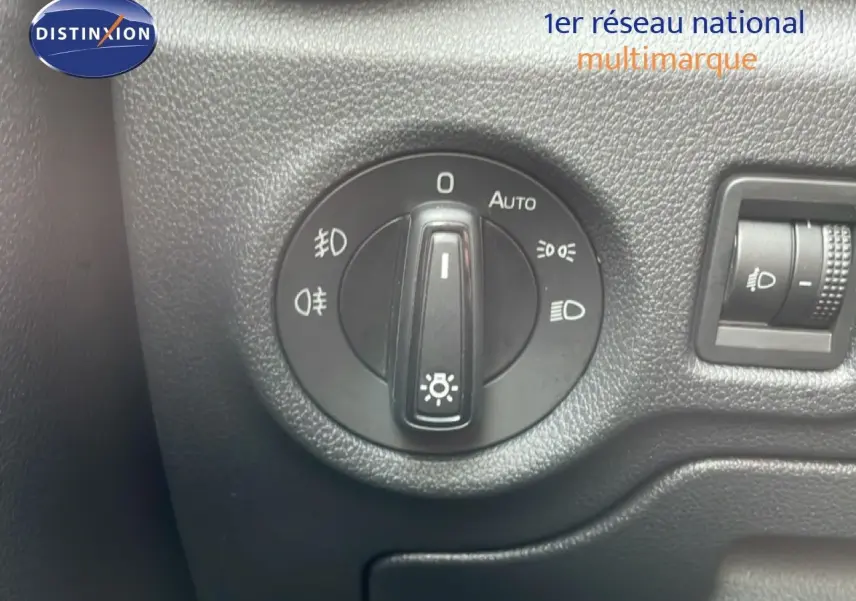 Gros plan sur le bouton de commande des phares dans l’habitacle noir d’une Skoda Fabia blanc glacier 2025.