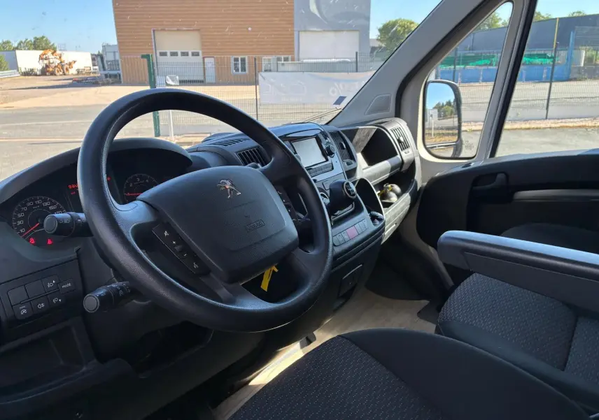 Vue intérieure côté conducteur du Peugeot Boxer cabine approfondie 2019, tableau de bord noir avec volant multifonction.
