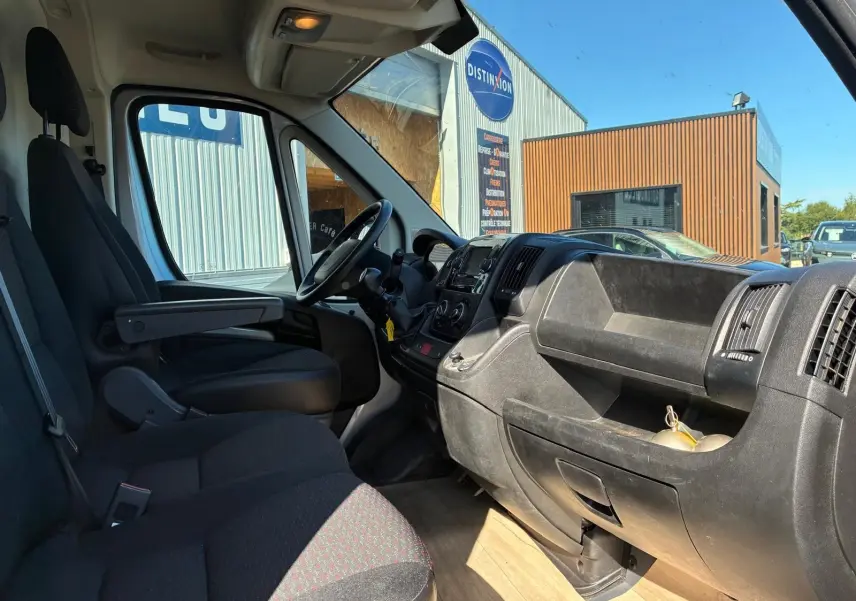 Vue intérieure côté conducteur du Peugeot Boxer cabine approfondie 2019, avec tableau de bord noir et sièges en tissu gris.