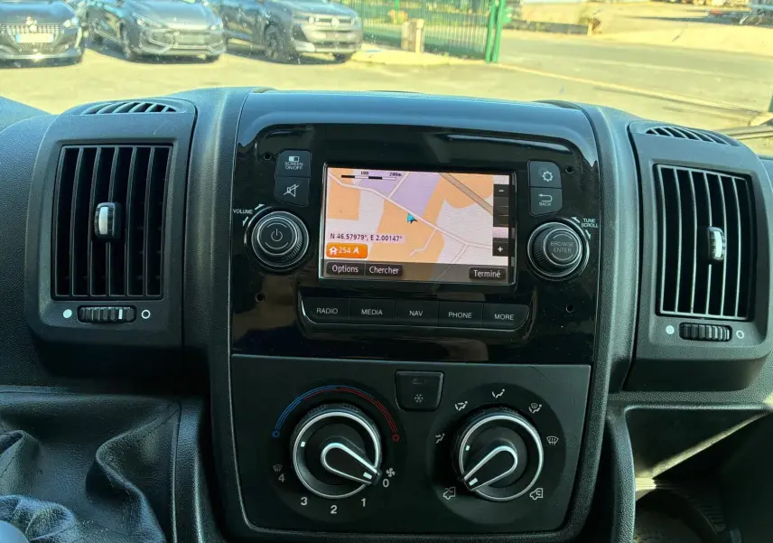 Vue rapprochée du tableau de bord noir du Peugeot Boxer cabine approfondie 2019 avec écran GPS allumé et commandes de climatisation.