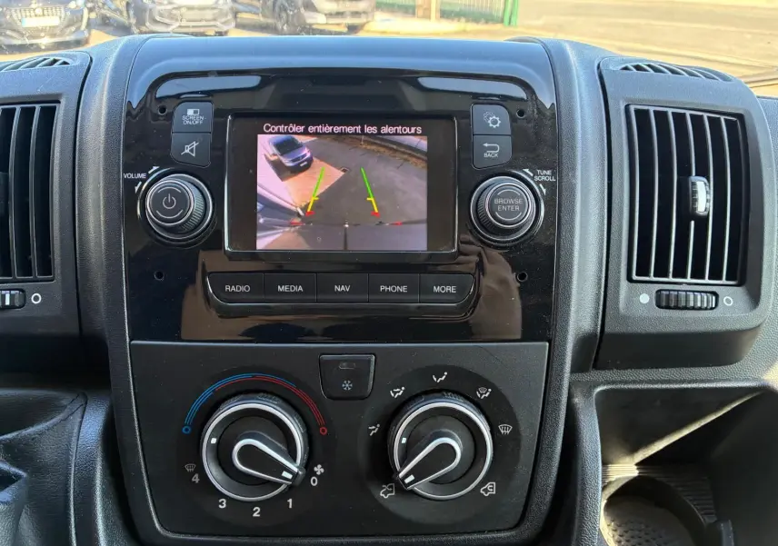 Vue rapprochée du tableau de bord du Peugeot Boxer 2019 avec écran de caméra de recul et commandes de climatisation.