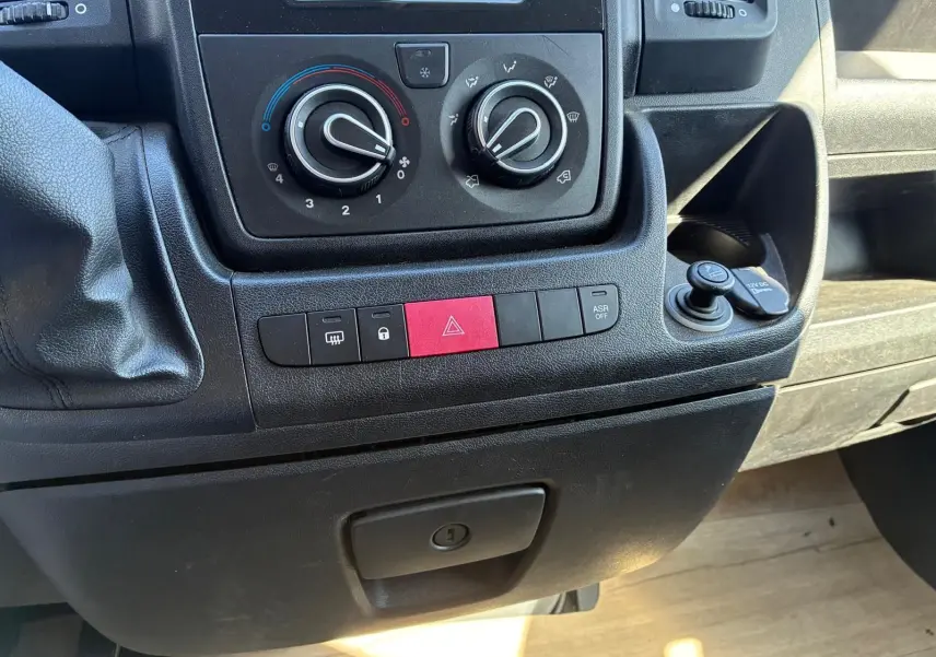 Vue rapprochée du tableau de bord gris du Peugeot Boxer cabine approfondie 2019, avec commandes clim et boutons rouges d’alerte.