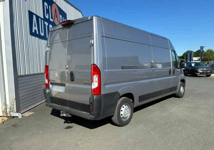 Peugeot Boxer cabine approfondie gris, vue 3/4 arrière droit, avec attelage et feux arrière rouges visibles.