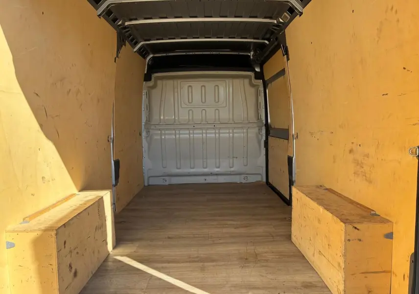 Vue intérieure de la zone de chargement du Peugeot Boxer gris, montrant l’espace vide avec parois en bois clair.